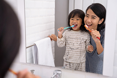 mom and daughter brushing their teeth together